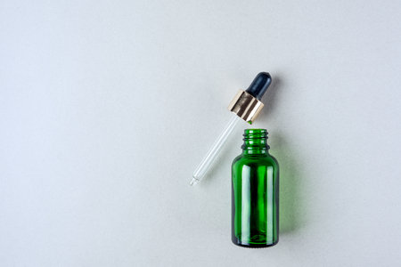 Minimalist photo of skin care, packaging for cosmetics. Green glass bottle with a pipette in pastel colors. Flat lay.の写真素材