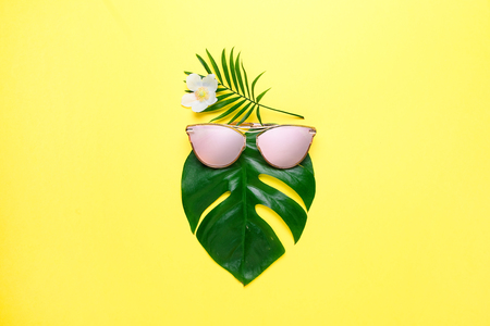 Tropical beach concept. Fashionable hipster Monstera in trendy glasses. Creative poster is bright yellow. copy spaceの写真素材