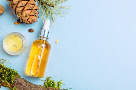 Organic cedar oil and cedar cone on a blue background. Flat lay. Beauty blogger conceptの写真素材
