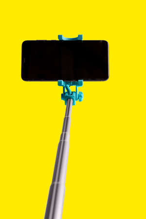 Monopod for selfie with smart phone. Selfie stick with smartphone isolated on yellow backgroundの写真素材