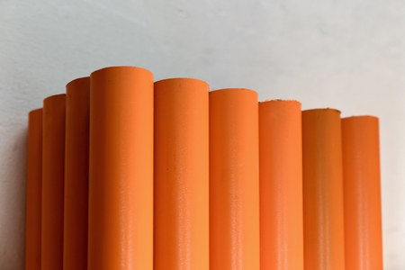 Metal pipes, stand upright. Painted in orange. Concept backgrounds of metal industry.