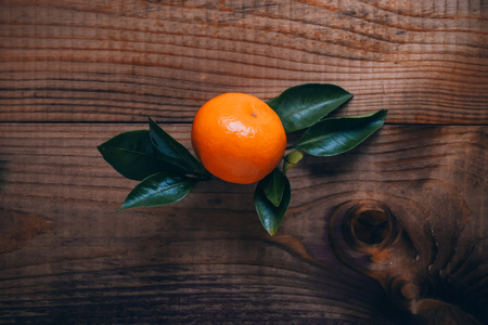 Ripe tangerine with green leaves on a dark wooden background. Christmas Flavorの写真素材