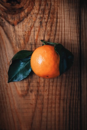Ripe tangerine with green leaves on a dark wooden background. Christmas Flavorの写真素材