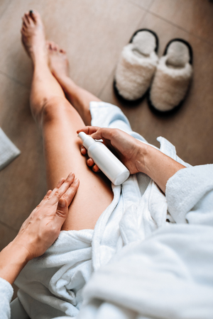 Body care. A young woman in the bathroom applies natural cream to her legs. Against varicose veins and leg edemaの写真素材
