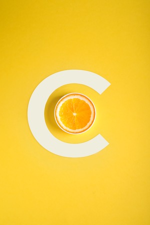 Concept of Vitamin C, orange and letter C on a yellow backgroundの写真素材