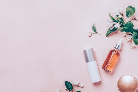 Pink natural cosmetics: oil, serum, cream, mask on background with flowers. Flat lay, minimalism.の写真素材