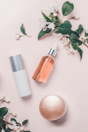 Pink natural cosmetics: oil, serum, cream, mask on background with flowers. Flat lay, minimalism.の写真素材