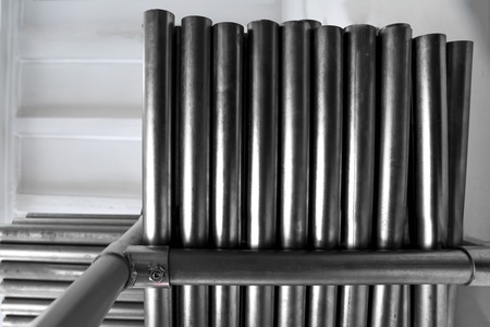 New metal pipes, with chrome plated coating, lie on storage shelves. Concept backgrounds of metal...