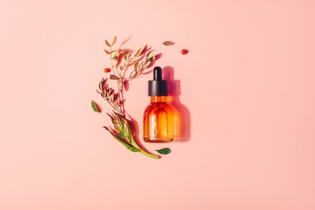 Bottle with natural serum with vitamins on a pink background. Cosmetic procedures for the faceの写真素材