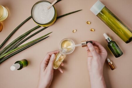 Woman cosmetologist cosmetics testing. Natural organic cosmetics. Serum hair mask. Flat lay pastel