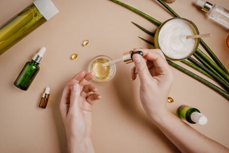 Woman cosmetologist cosmetics testing. Natural organic cosmetics. Serum hair mask. Flat lay pastel