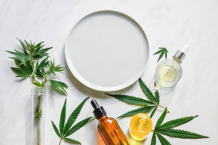 Various glass bottles with CBD oil, THC tincture and hemp leaves on a marble background. Copy space, mockup. Cosmetics CBD oil.の写真素材