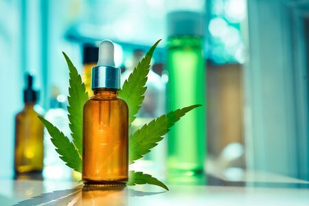 CBD OIL glass bottle, tincture and hemp leaf on a background of a medical laboratory. Concept of legal medicineの写真素材