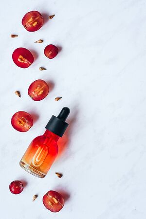 Grape seed oil. Creative still life of grapes, seeds and a bottle on a light background. Flat lay.の写真素材