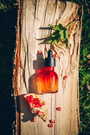 Pomegranate seed oil in glass bottle on wooden background. Flat lay, minimalism. Concept of anti-aging skin care.の写真素材