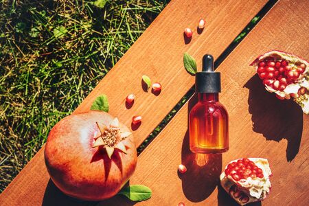 Pomegranate seed oil in glass bottle on wooden background. Flat lay, minimalism. Concept of anti-aging skin careの写真素材