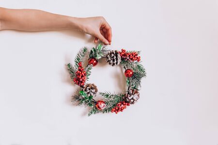 Wreath frame from pine and Christmas decor in female hands on light background. Flat lay, elegant style. Christmas preparation for holiday Minimalismの写真素材