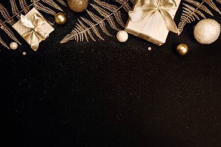 Christmas background. Holiday Gifts in white boxes with a festive decor and shiny branches on a black background with glitters. Flat lay, top view, copy spaceの写真素材