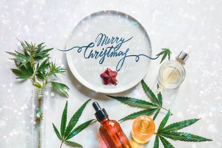 Glass bottles CBD oil, THC tincture and hemp leaves In a Christmas decoration. Festive background for cannabis. Flat layの写真素材