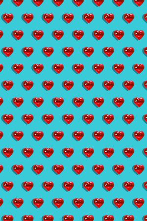 Valentine's day background. Pattern of glass red hearts on a blue background. Card minimalism,...