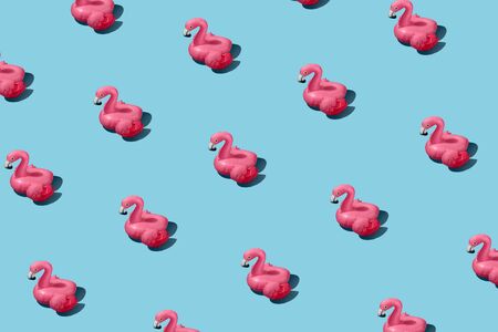 Fashionable pattern with inflatable pink flamingo on a blue background. Summer vacation concept and...
