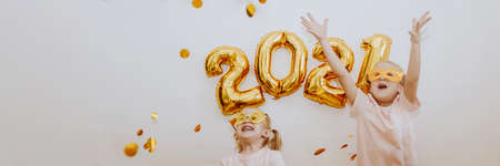 Three little girls are enjoying the flying golden confetti. Celebrating at home 2021. Concept for Christmas and New Year. Bannerの写真素材