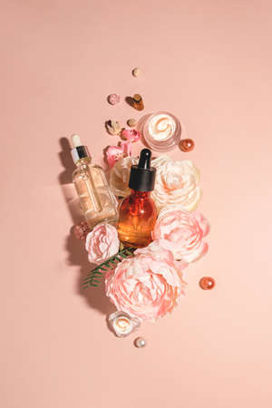 Natural cosmetics, bio serum and organic oils for skin care combined with flowers. Trendy monochrome pastel peach background. Concept of natural skin care and organic perfumeの写真素材