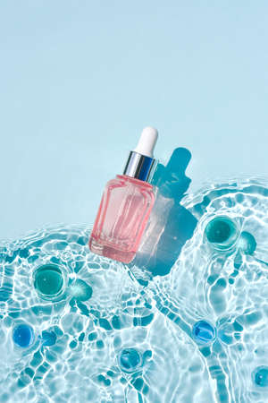 Mockup cosmetic pink bottle with pipette, water surface with waves Moisturizing advertising conceptの写真素材