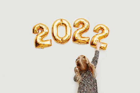 Little girl decorates wall of house with golden numbers 2022の写真素材