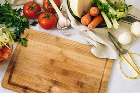 Vegan background Various raw vegetables around a cutting wooden boardの写真素材