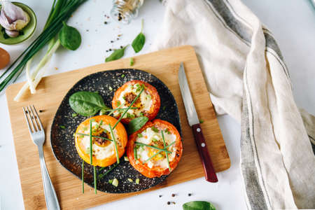 Three Large baked tomatoes with egg and herbs.の写真素材