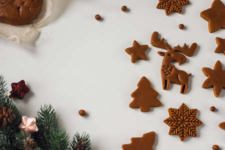 Many blanks of gingerbread cookies of different shapes on table with Christmas decorの写真素材
