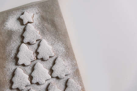 Gingerbread Christmas tree sprinkled with powdered sugar on parchmentの写真素材