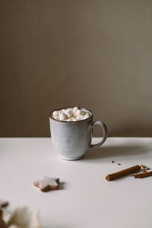 Hot cocoa with marshmallows on a white table with gingerbread.