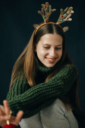 Teenager girl with Christmas deer horns in green sweater, smilingの写真素材