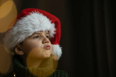 Cute boy in green sweater and a Santa hat, grimacing.の写真素材