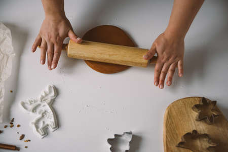 Female hands roll out raw ginger dough with a rolling pin on a white tablの写真素材