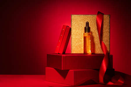 Gold cosmetics on red podium with gift boxes and decorの写真素材