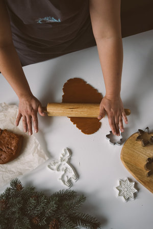 Female hands roll out raw ginger dough with a rolling pin on a white tablの写真素材