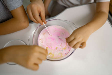 Children, girl, boy are having fun at home, experimenting with milk and paints