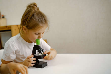 Girl 4 years old, at home in the room looks through microscopeの写真素材