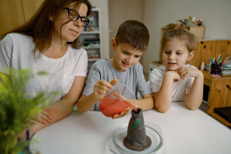 Mom and children at home are conducting an experiment with a volcanic eruption.の写真素材
