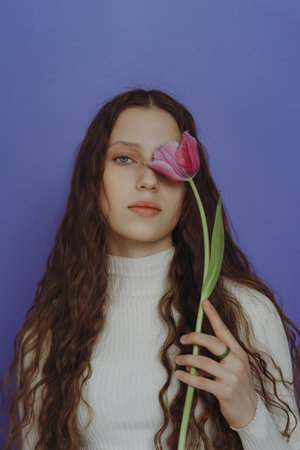 Portrait of a young girl with long hair and a tulip flowerの写真素材