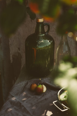 A large bottle of fruit cider on a rustic table with a harvest of pears, on an autumn sunny dayの写真素材