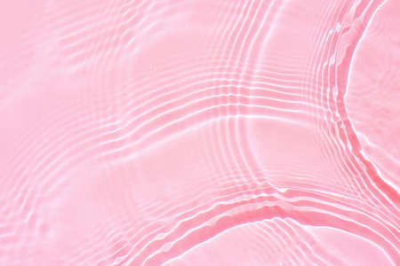 Background, texture of transparent pink water with ripples and wavesの写真素材