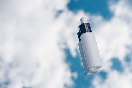 White bottle mockup with pipette for serum with hyaluron, collagen on blue sky background with clouds.の写真素材