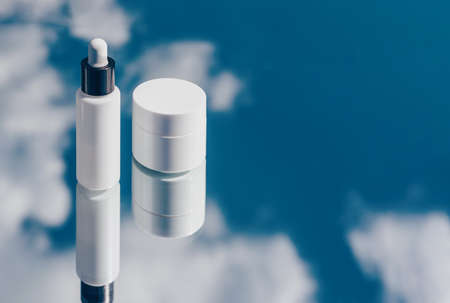 Natural oxygen cosmetics, white mockup of a bottle with a pipette and a jar of cream on blue sky backgroundの写真素材