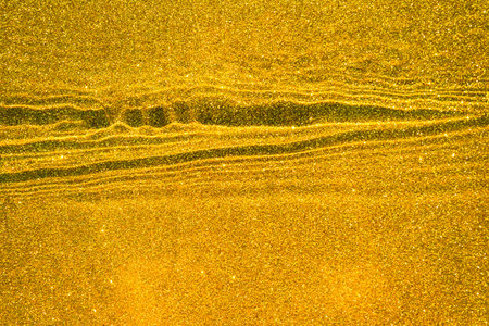 Abstract yellow background with golden sand texture underwater, with waves and ripplesの写真素材