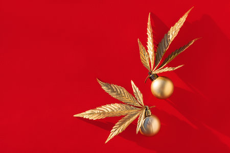 Golden Christmas balls with golden leaves of marijuana on red background.の写真素材