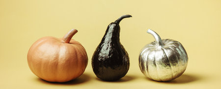 Minimal Harvest background concept, pumpkins of different shapes and colors on yellow backgroundの写真素材
